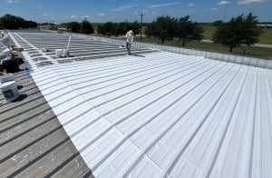 Technician Applying Silicone Roof Costing on Commercial Metal Roof